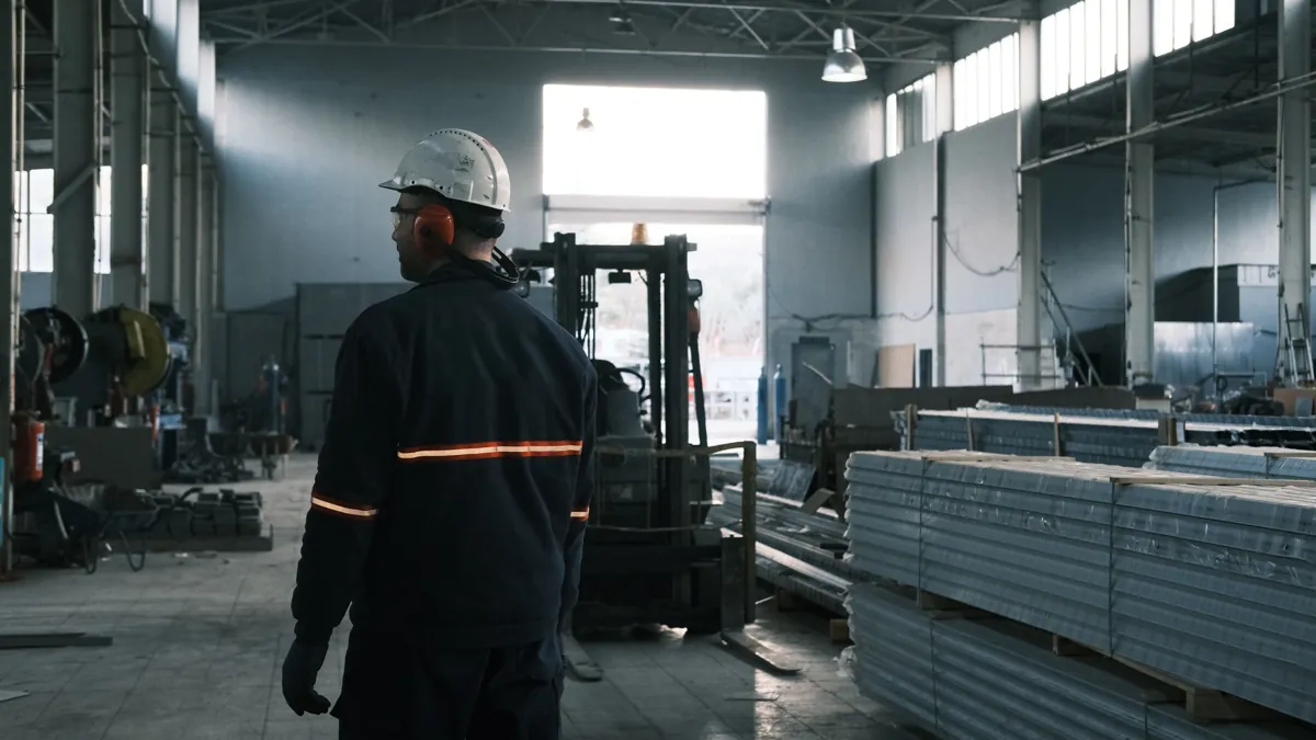 Trabalhador com capacete e protetor auricular em um galpão industrial